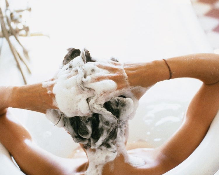 Woman lathering hair in bathtub