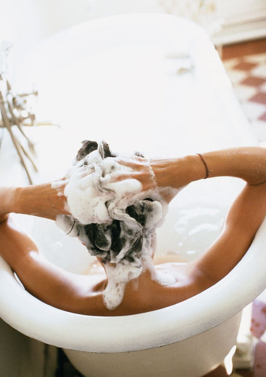 Woman lathering hair in bathtub